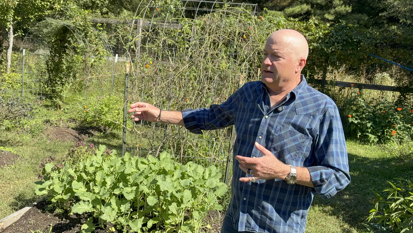 Maurice gesturing toward a bed of greens