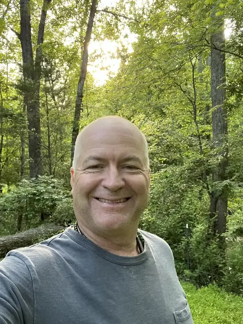 Maurice Werness smiling on a wooded trail